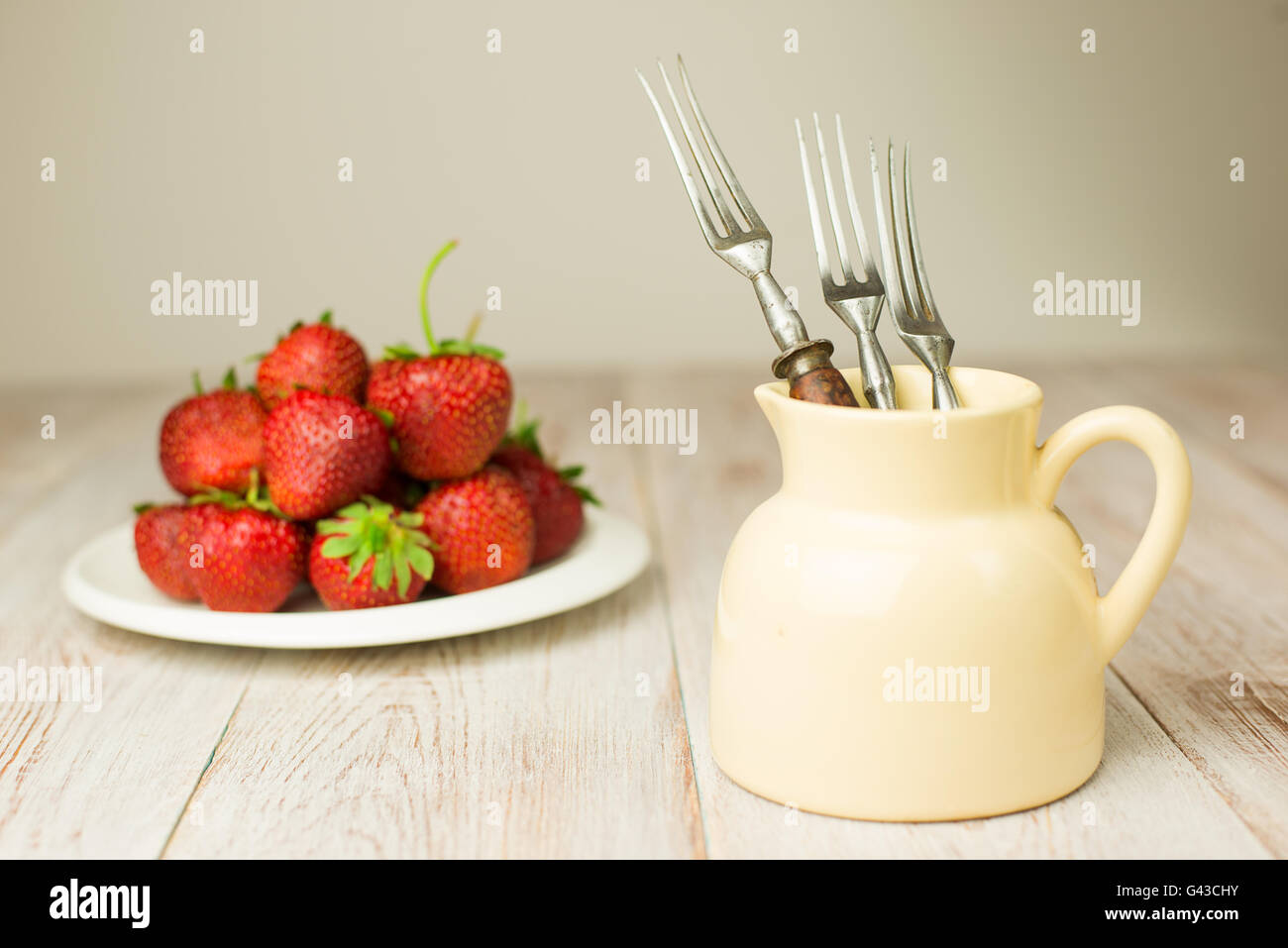 Three forks and ripe red strawberries on a white plate Stock Photo