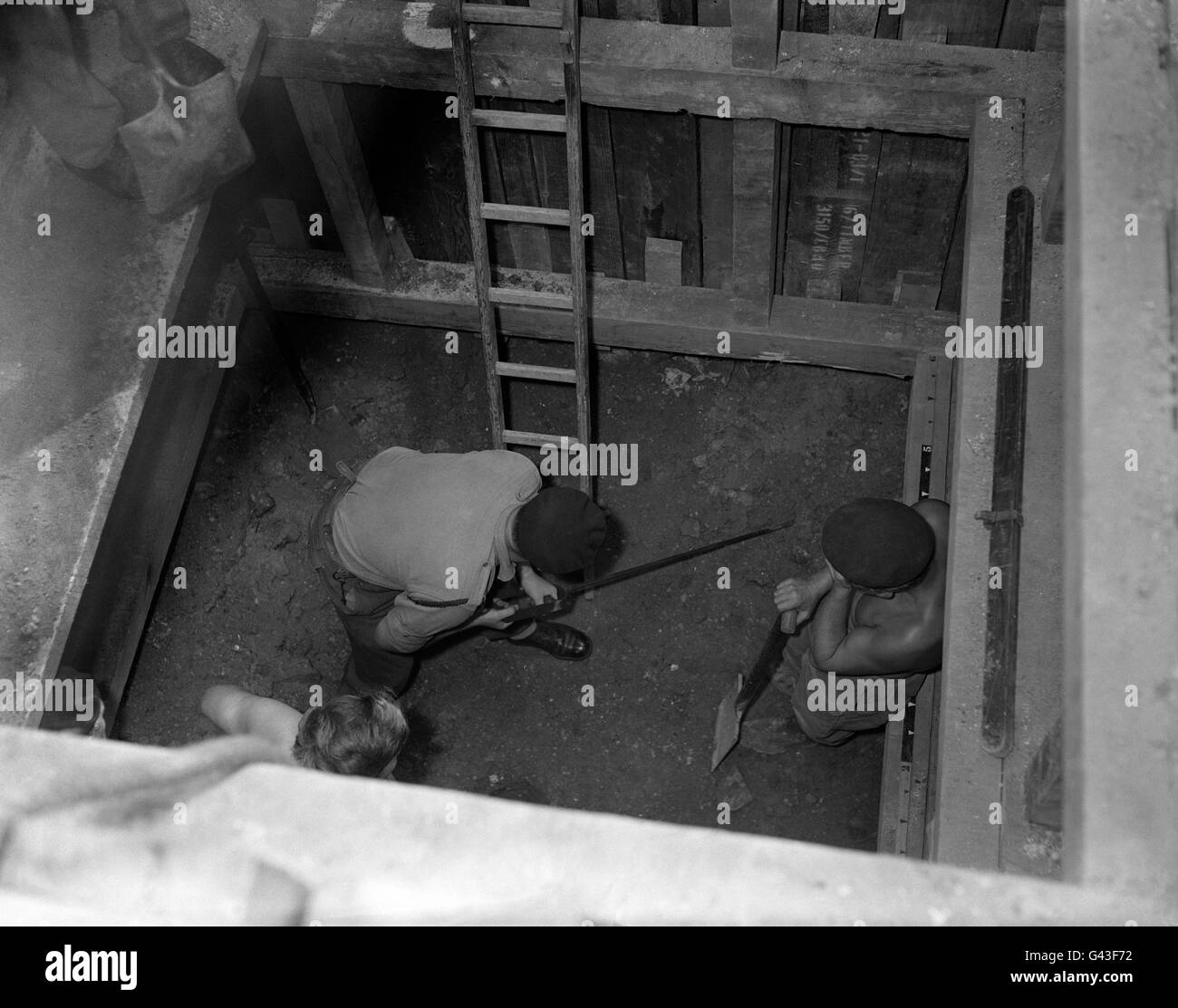 Corporal Gordon Townley at the bottom of a deep excavation probing for a German bomb near the Tate Gallery, London. Stock Photo