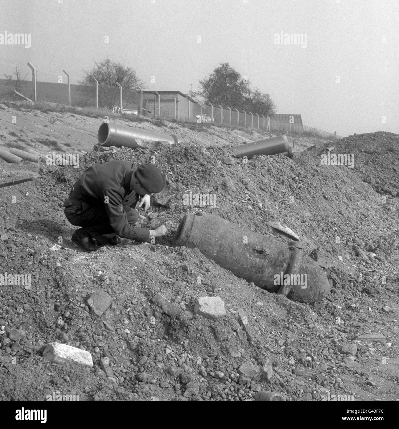 Two Royal Air Force men from RAF Debden, Essex, take a close look at a 1,000-pound bomb unearthed at Southall Lane, Heston and Isleworth, Middlesex by men working on excavations in connection with the extension of the M4 motorway. Stock Photo