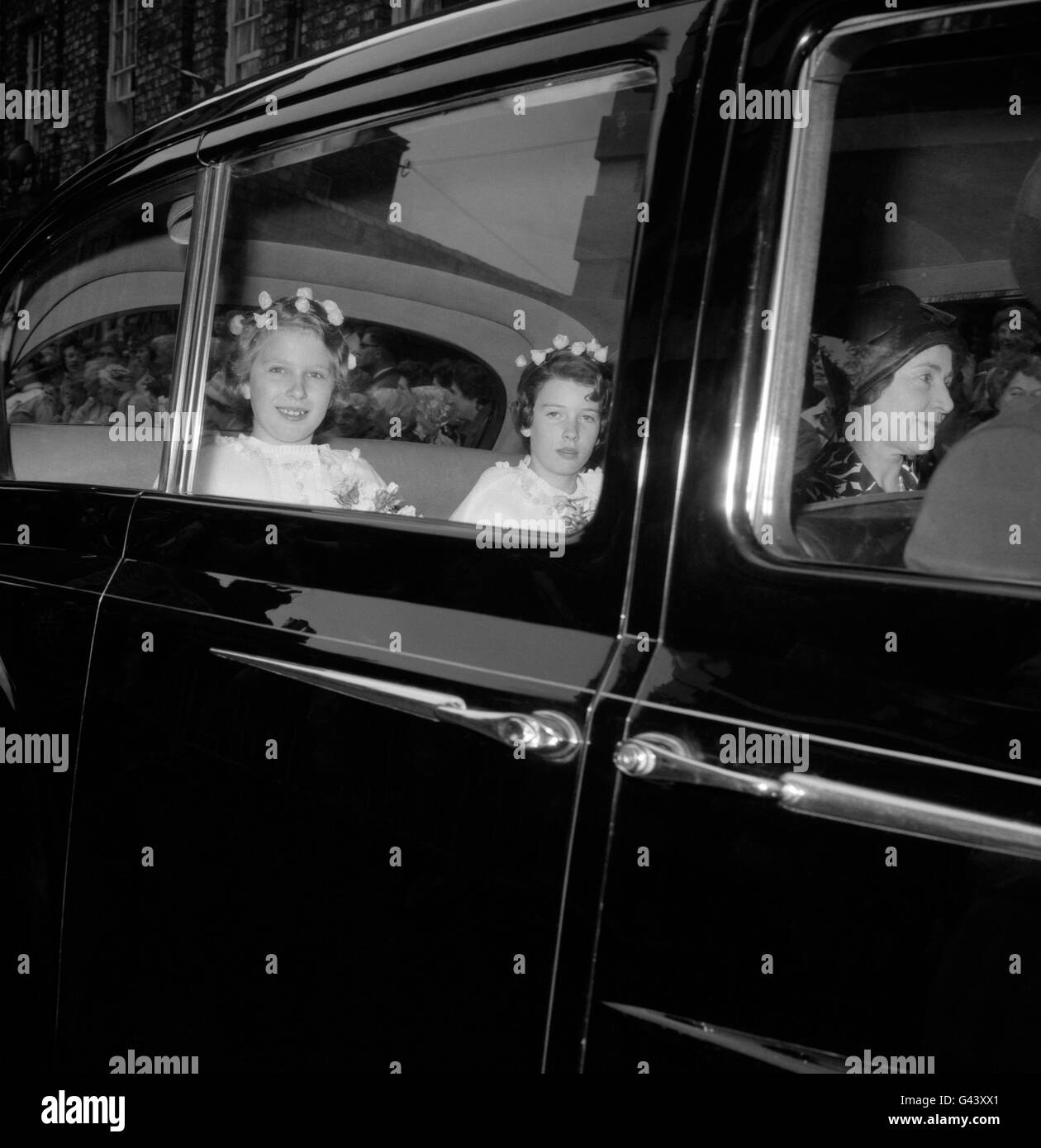 Sparkling-eyed under her headdress of scattered yellow rosebuds, Princess Anne and another of the bridesmaids, Miss Sandra Butter, drive away from York Minster after the wedding of the Duke of Kent and Miss Katherine Worsley. Stock Photo