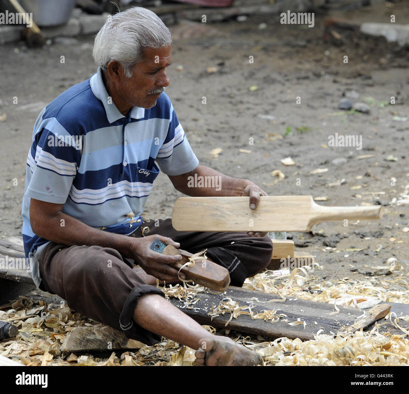A man makes cricket bats next to the road in Nagpur city centre, India. Stock Photo