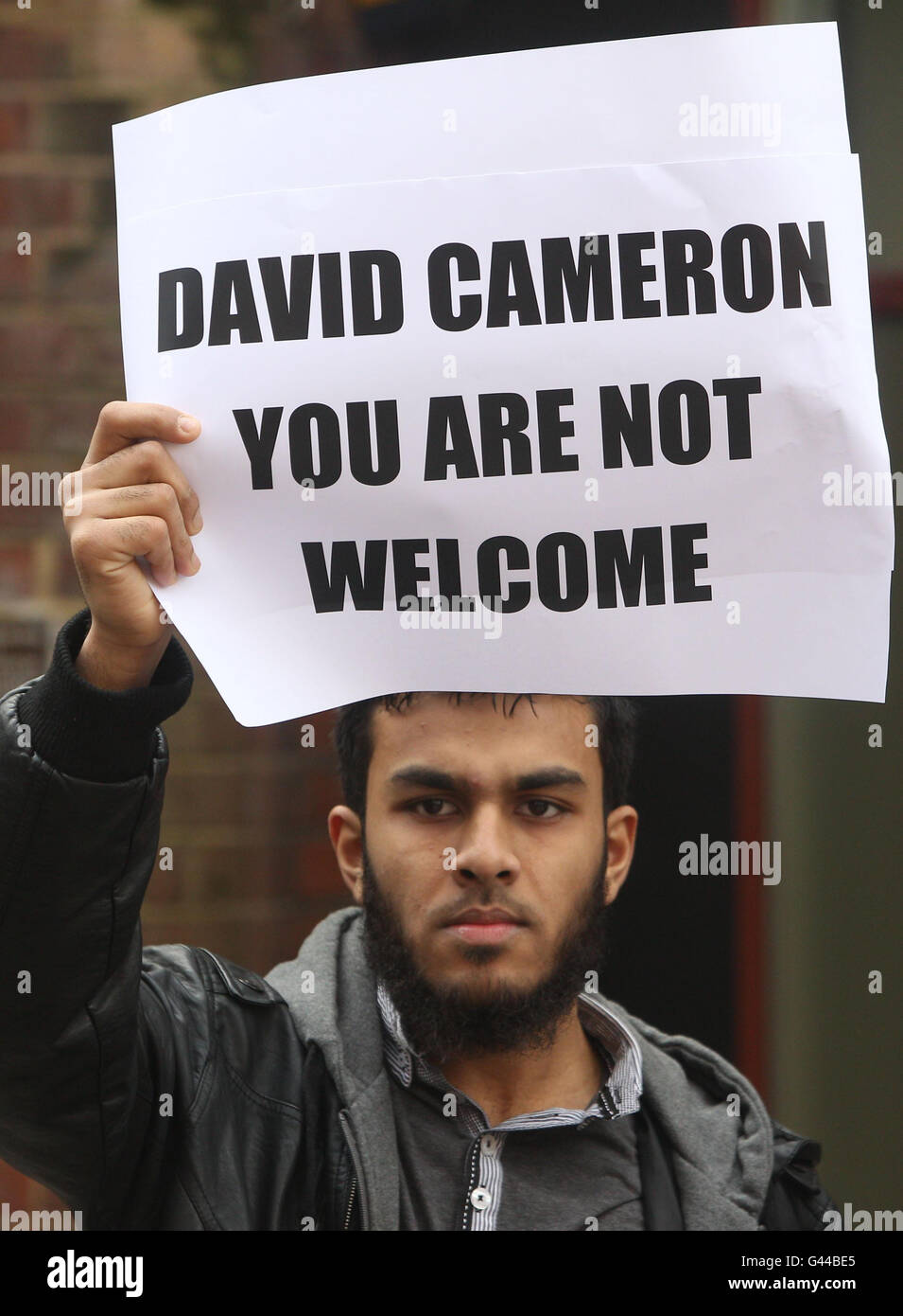 A protestor holds a sign outside Toynbee Hall (name not known) in East London, where Prime Minister David Cameron made a speech on welfare reform. Stock Photo