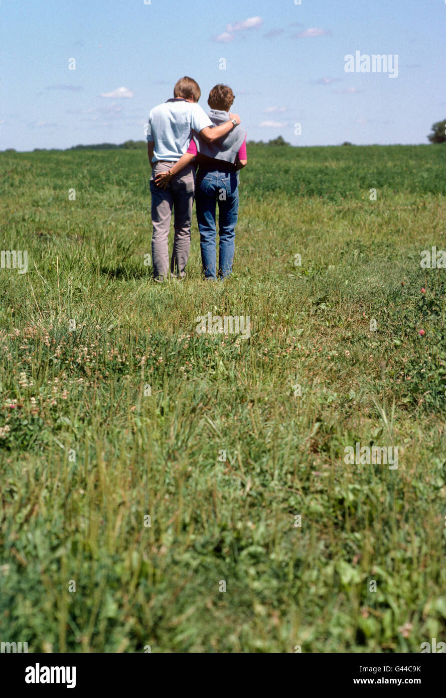 Young couple walking across grass covered field Stock Photo