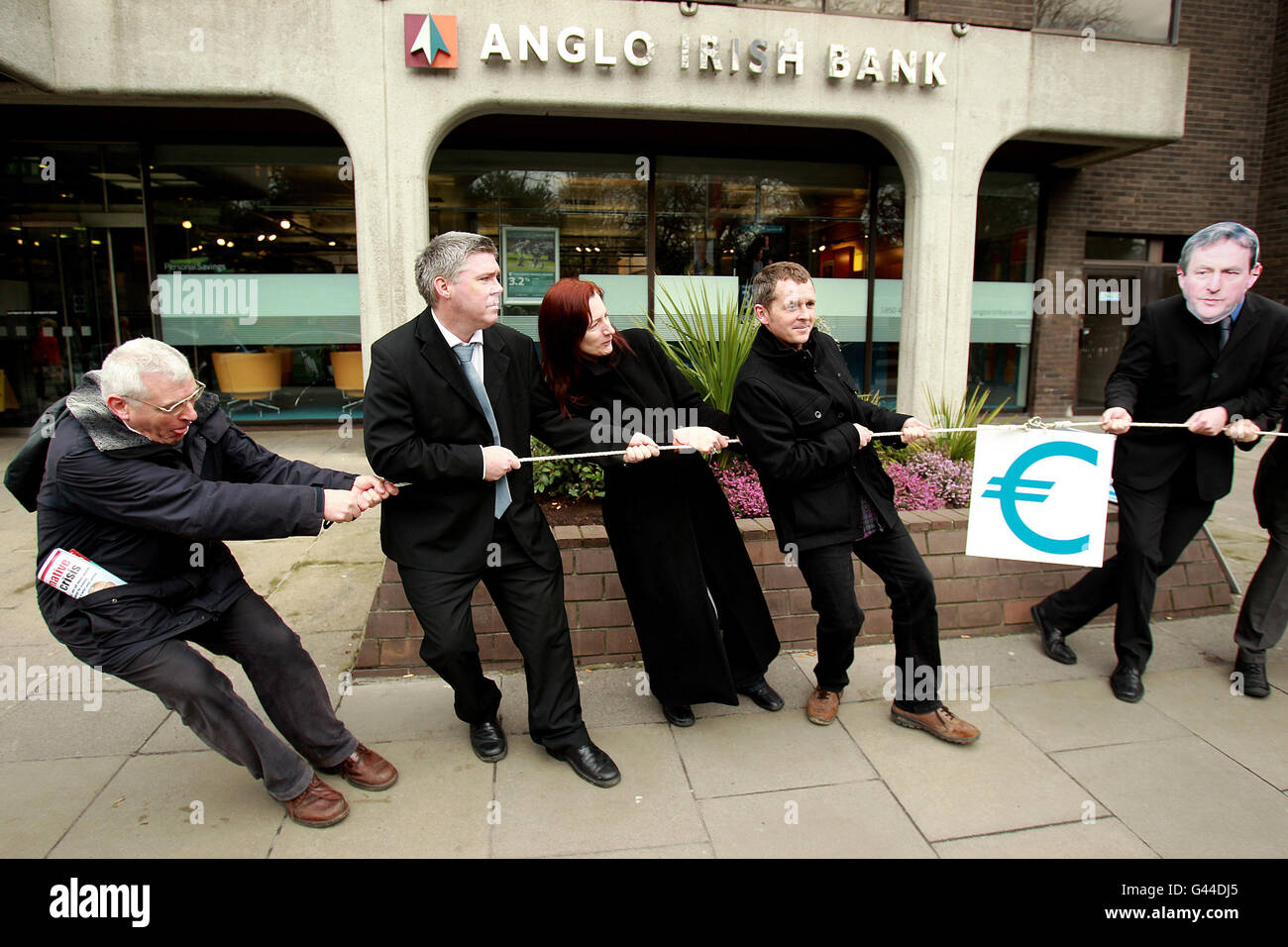 United Left Alliance candidates (left to right) Joe Higgins, Brian Greene, Claire Daly and Richard Boyd Barrett in a tug of war with United Left supporters wearing Enda Kenny, Michael Martin and Eamon Gilmore masks, during a campaign stunt outside the offices of Anglo Irish Bank in Dublin. Stock Photo