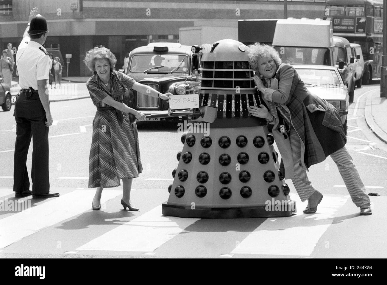 Dr Who actor Colin Baker pushing a Dalek in the direction of Women's Hour presenter Sue McGregor in London. The Dalek is to be auctioned at Christie's in aid of Radio Sudan Appeal organised by BBC Radio Woman's Hour and the British Red Cross. Stock Photo
