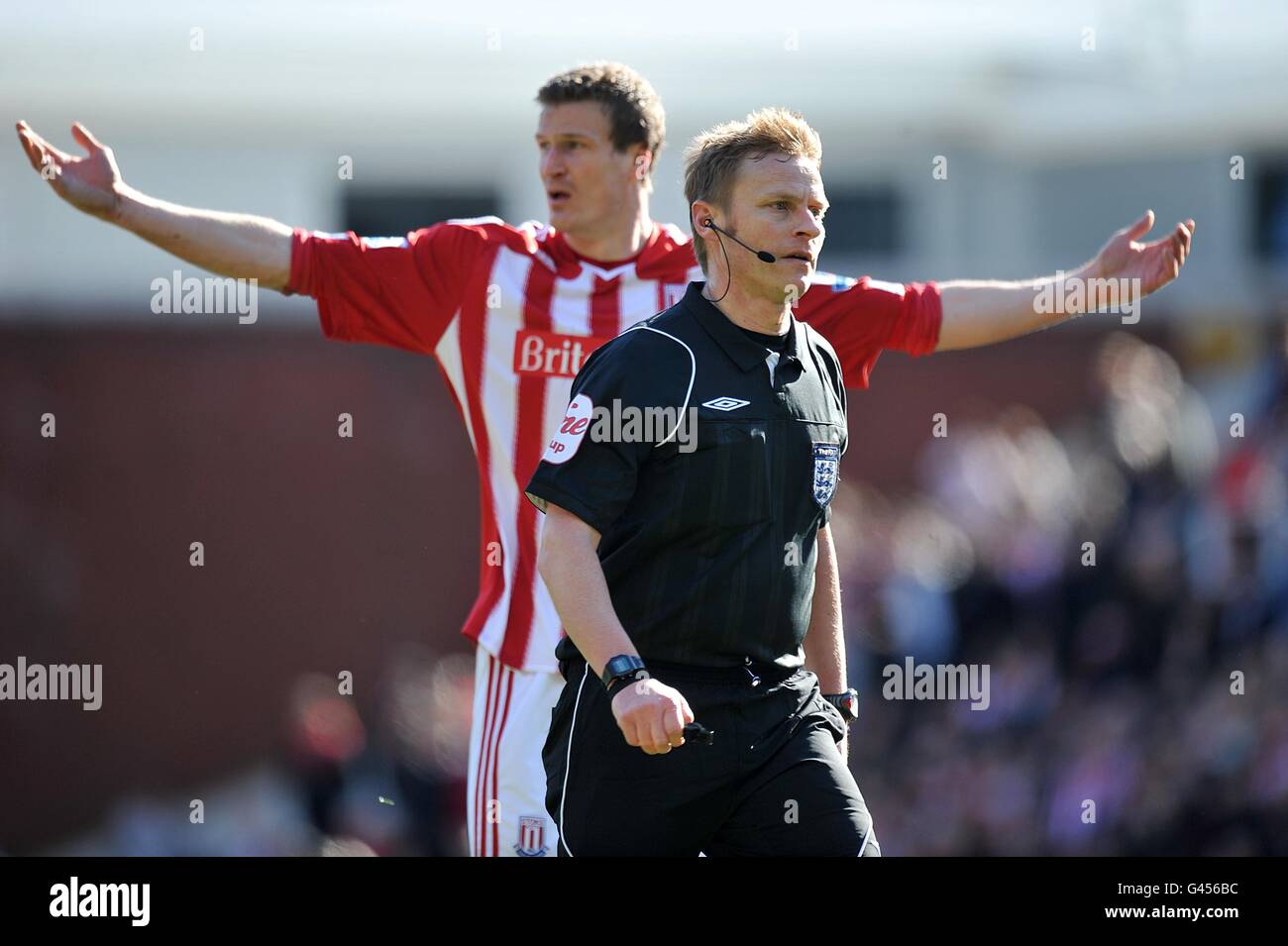 Stoke City's Robert Huth (back) holds his arms up in disbelief as match referee Mike Jones walks away from his team's protests regarding West Ham United's opening goal. Stock Photo