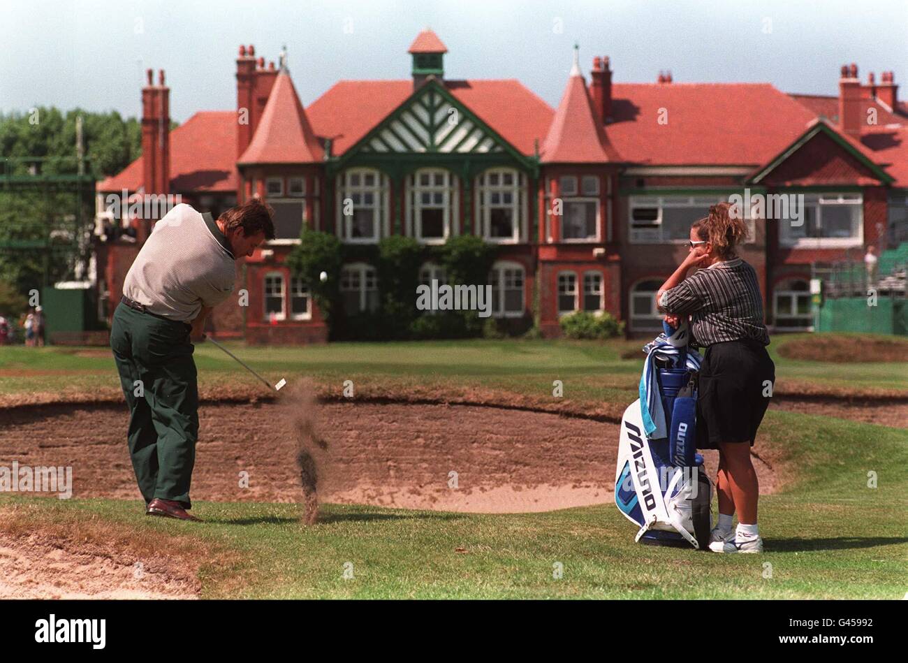 Championship Favourite Nick Faldo chips from in front of a bunker as he approaches the 18th green under the watchful gaze of his caddy Fanny Sunesson to complete his practice round today (Monday) at the Royal Lytham & St Annes golf course prior to this week's British Open. By Adam Butler/PA. Stock Photo