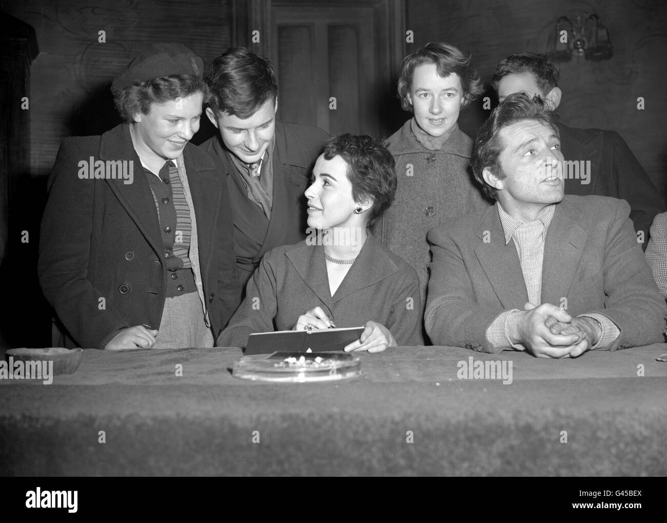 Evelyn Sherbell, 12, left, receives an autograph from actress Claire Bloom at a Christmas Holiday Lecture for Children. They heard Claire Bloom and Richard Burton, right, talk on Shakespeare's Welshmen, at Wyndham's Theatre. Stock Photo