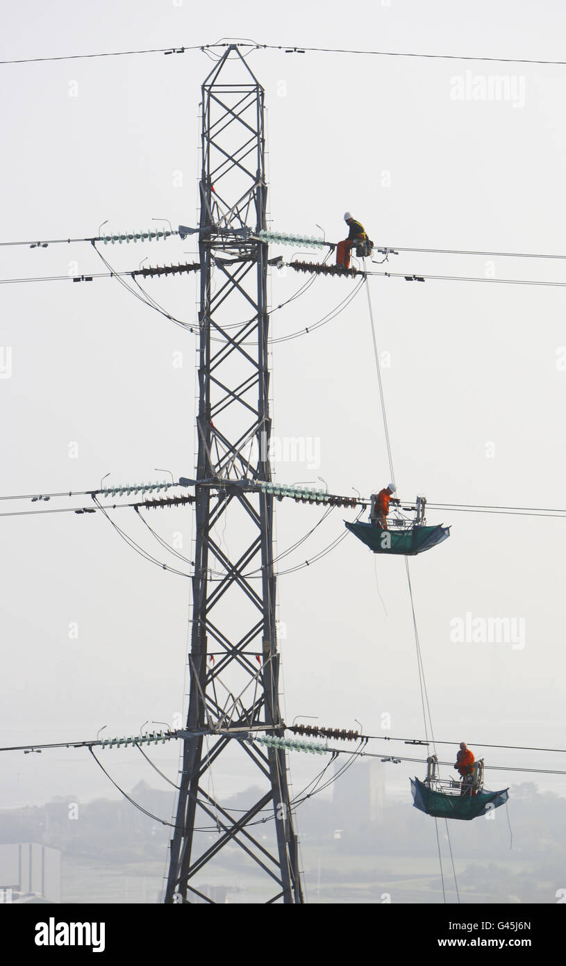 Engineers work in gondolas attached to high voltage power lines high