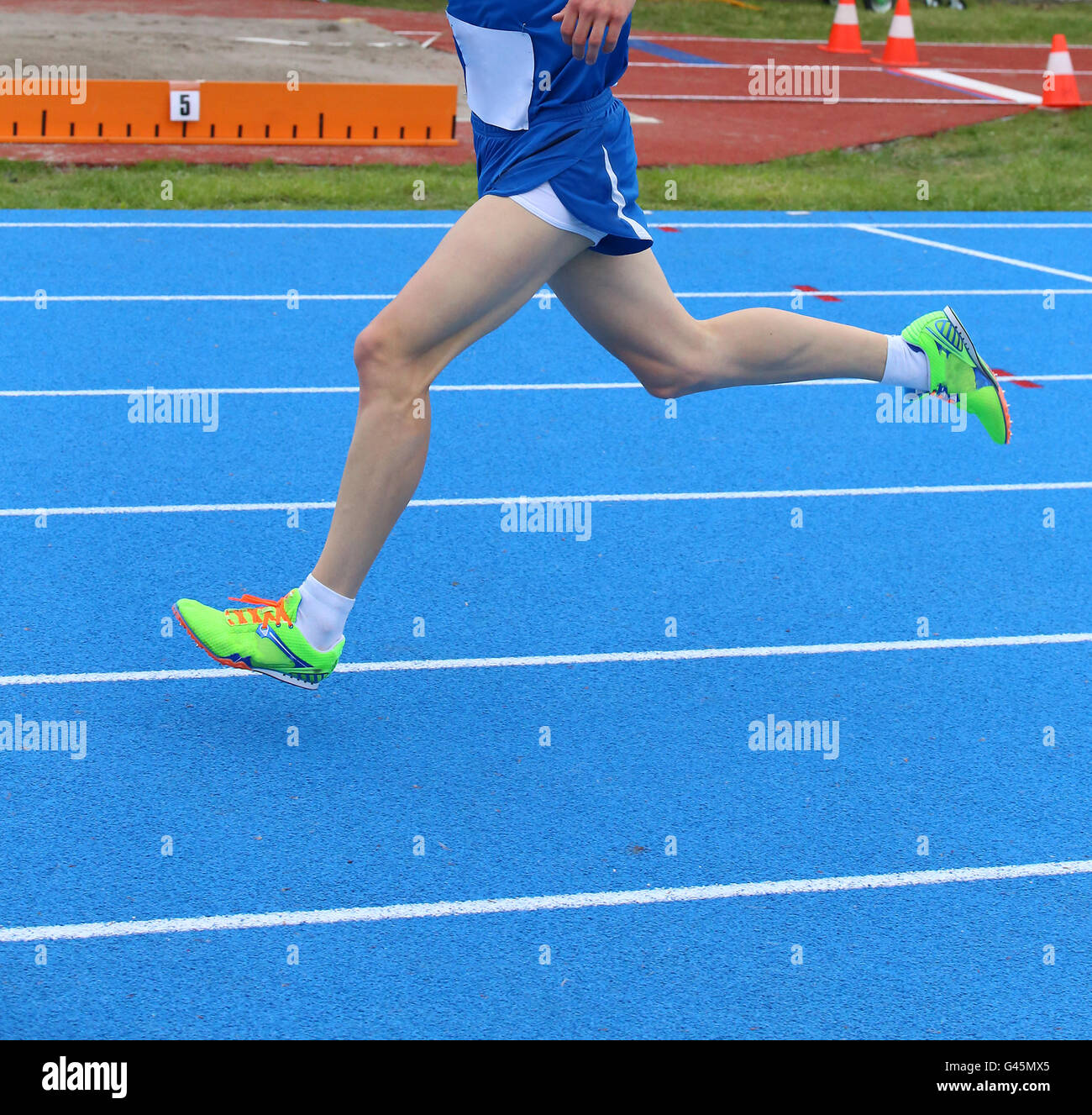 long legs of fast runner runs into the blue in athletics track Stock