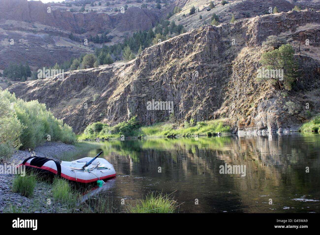 Morning light dances off the still water of the John Day River and canyon walls Stock Photo