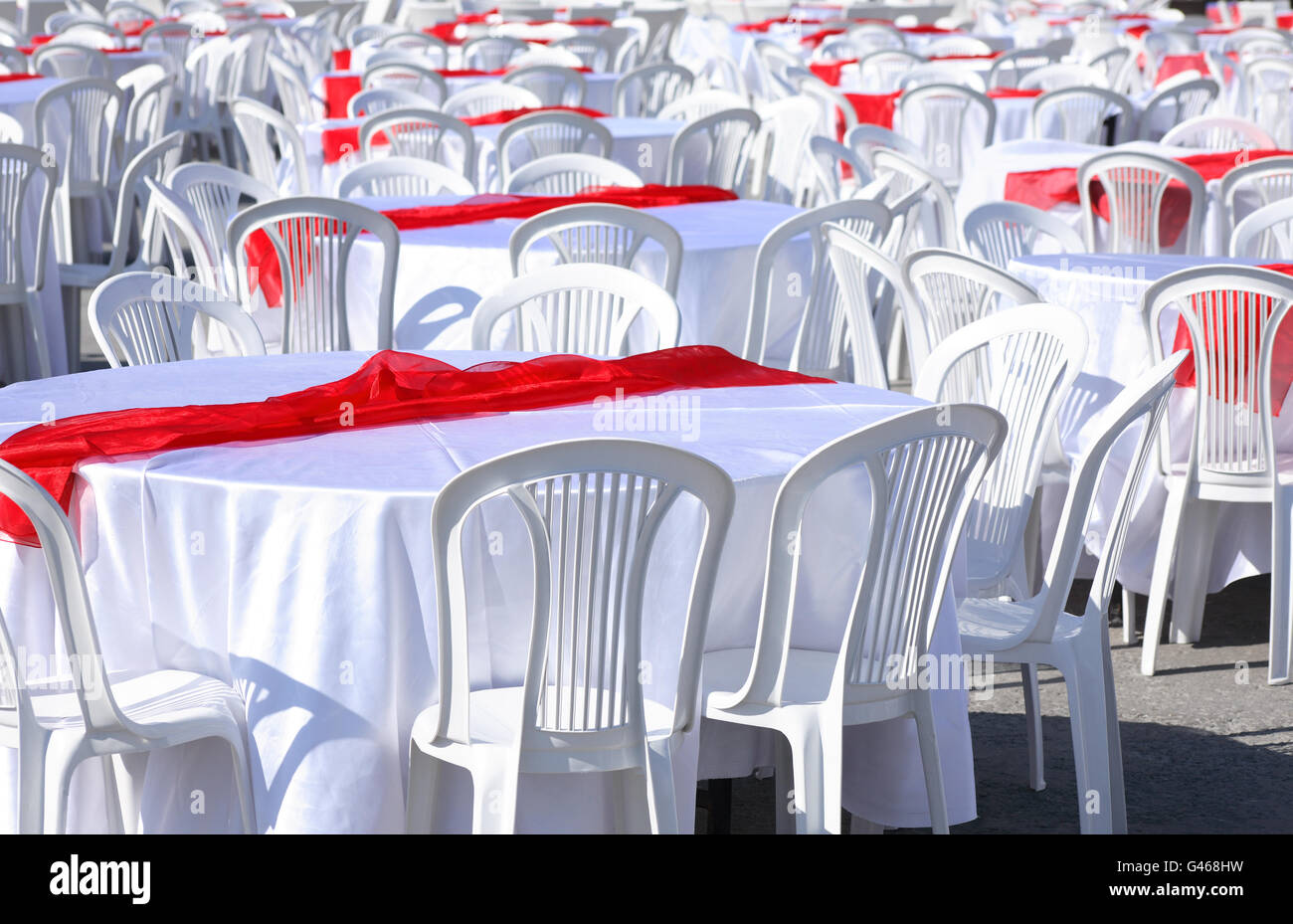 Empty tables covering with white tablecloth and red bands outdoor Stock Photo