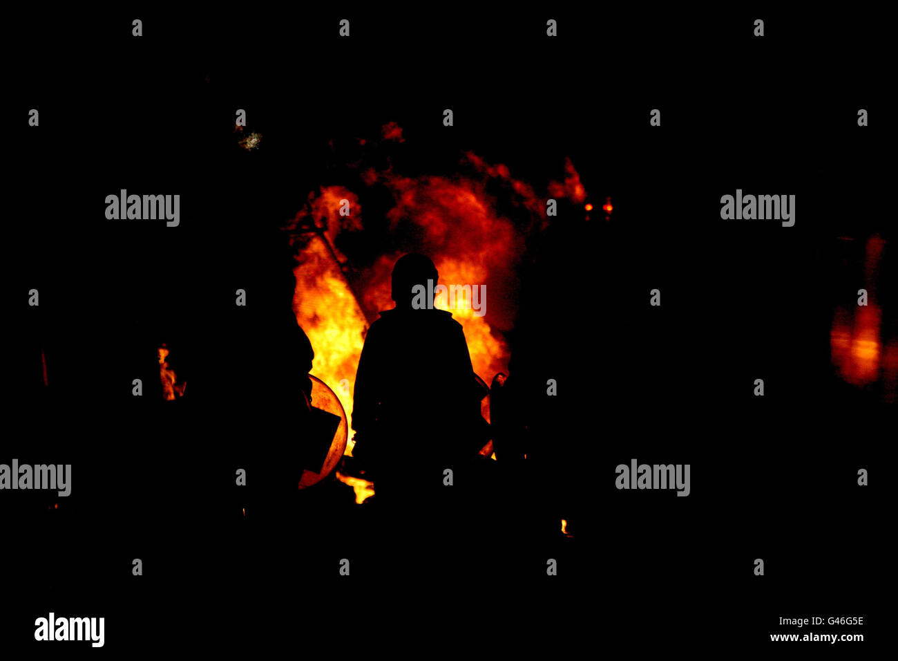 Police officers in riot gear stand in front of a fire in Piccadilly after the TUC March For The Alternative at Oxford Circus in London, a protest against Government spending cuts. Stock Photo