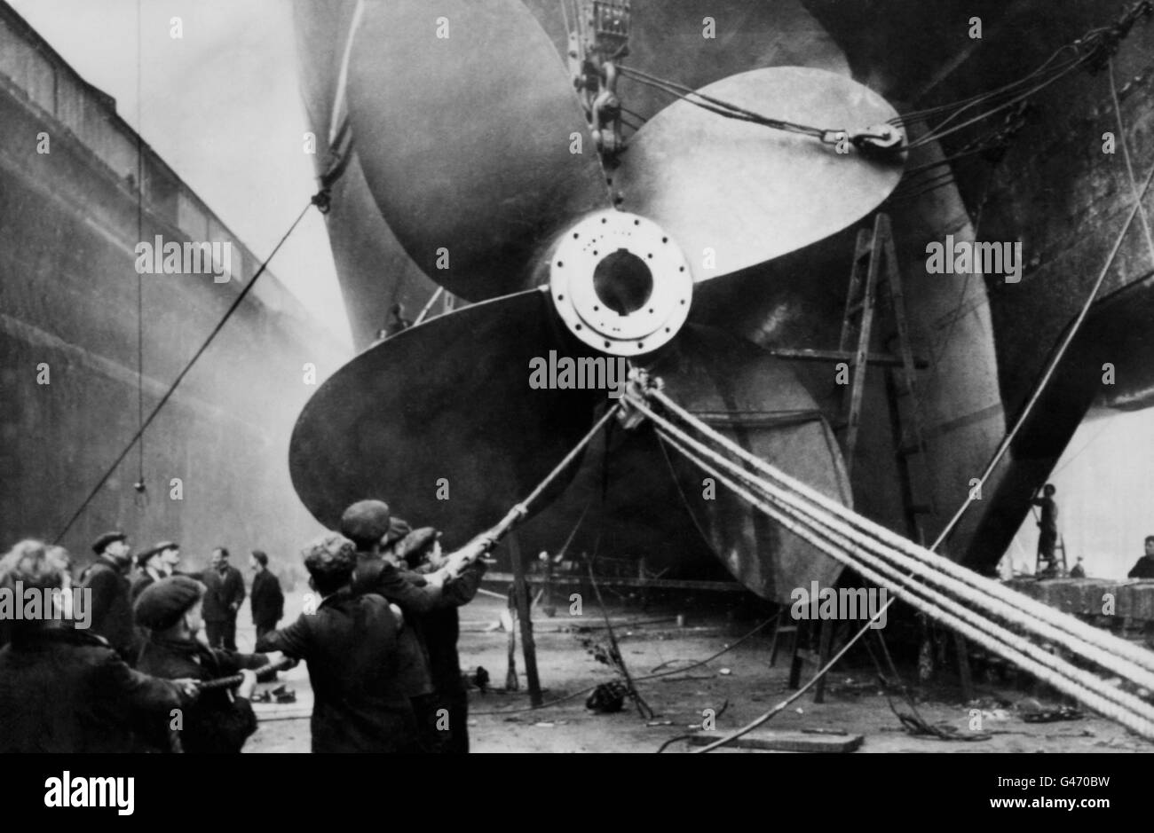 A delicate task as workmen hold carefully to the guide rope as a new propeller of manganese bronze, 19 feet 3 inches in diameter, is fitted to the Cunard liner RMS Mauretania, at Gladstone Dock, Liverpool. Stock Photo
