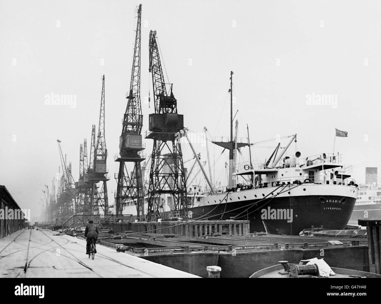 Idle cranes and a ship on which no activity is visible, seen in the King George V Dock as the number of men involved in the London docks strike reached 14, 238. Stock Photo