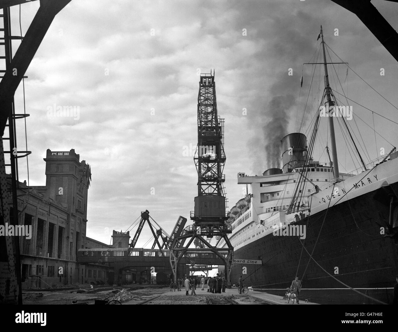 Making her first post-war call at Cherbourg, the giant 'RMS Queen Mary' eases alongside the rebuilt Quai de France to embark passengers for New York. Stock Photo