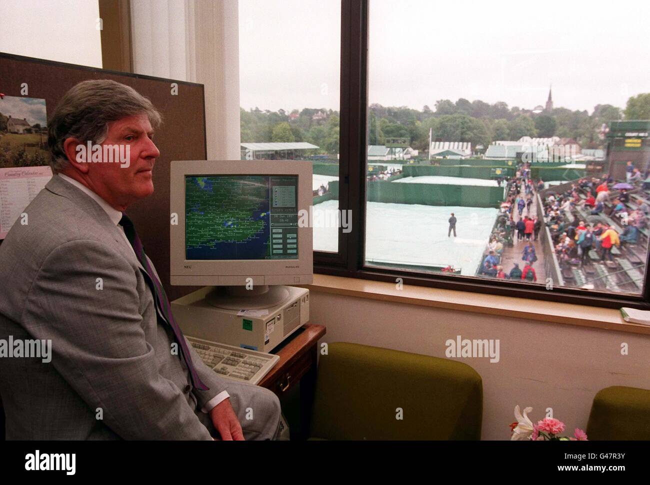 Wimbledon Tournament referee Alan Mills over looks the wet covered outside courts while glancing at the Meteorological Office's 'MIST' computer, which shows precisely the state of the weather around the country. A decision will be made later today (Sat), whether Wimbledon will open tomorrow, usually a rest day, to try and catch up on the 250 plus unplayed matches. Photo by Adam Butler/PA/EDI Stock Photo