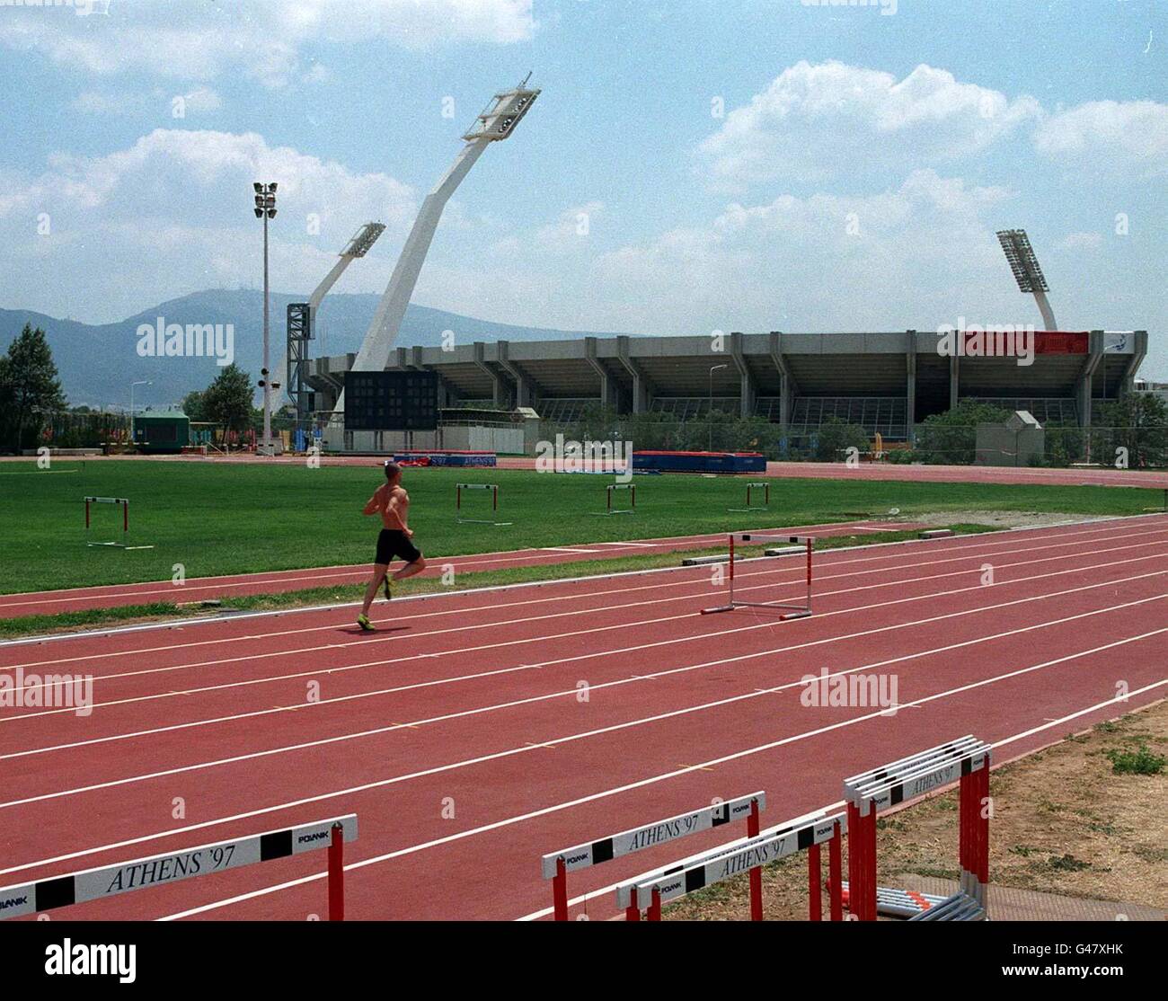 Training hard. Ian Mackie on the training grounds near to the Olympic Stadium in Athens (background) today (Weds) where he will try to emulate Linford Christie who he has replaced as the British hope in the 100m. Photo John Giles.PA. Stock Photo