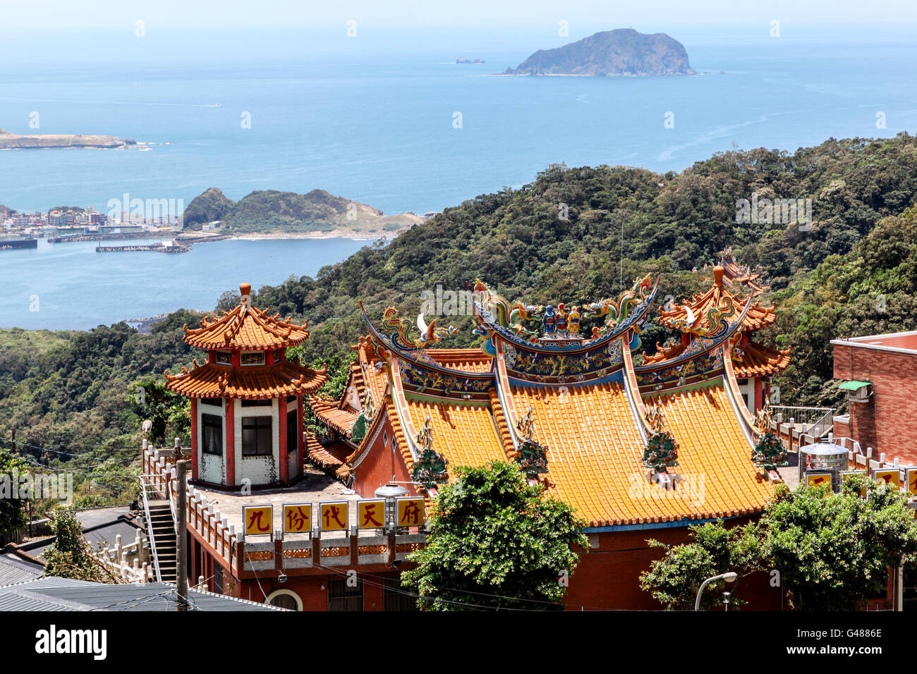 The colorful intricate rooftop of a Chinese temple on the hillside in Jiufen, New Taipei City, overlooks the shores of Taiwan on Stock Photo