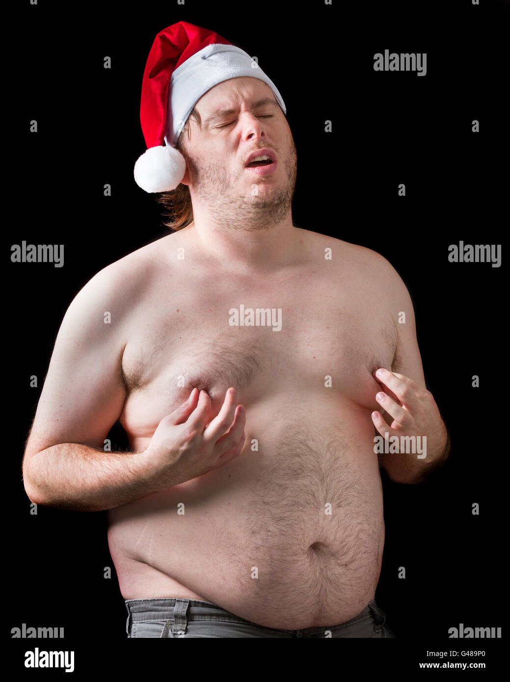 Fat man playing a naughty Santa Claus wearing his hat while being topless  and grabbing his nipples making a funny face. What a i Stock Photo - Alamy