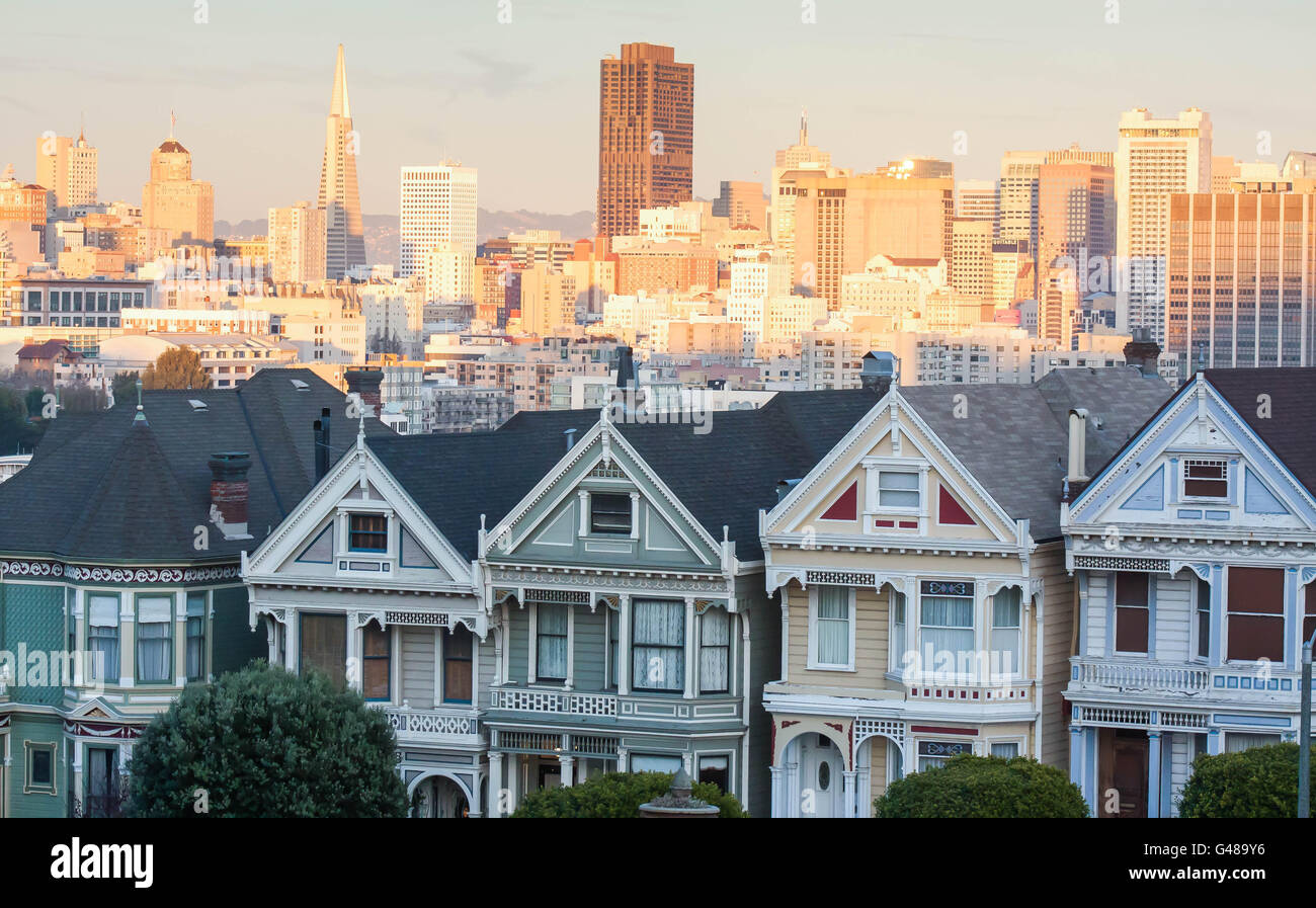 San Francisco, California, sunset with Iconic Painted Ladies Victorian era houses in Foreground, skyline bathed in gold light Stock Photo