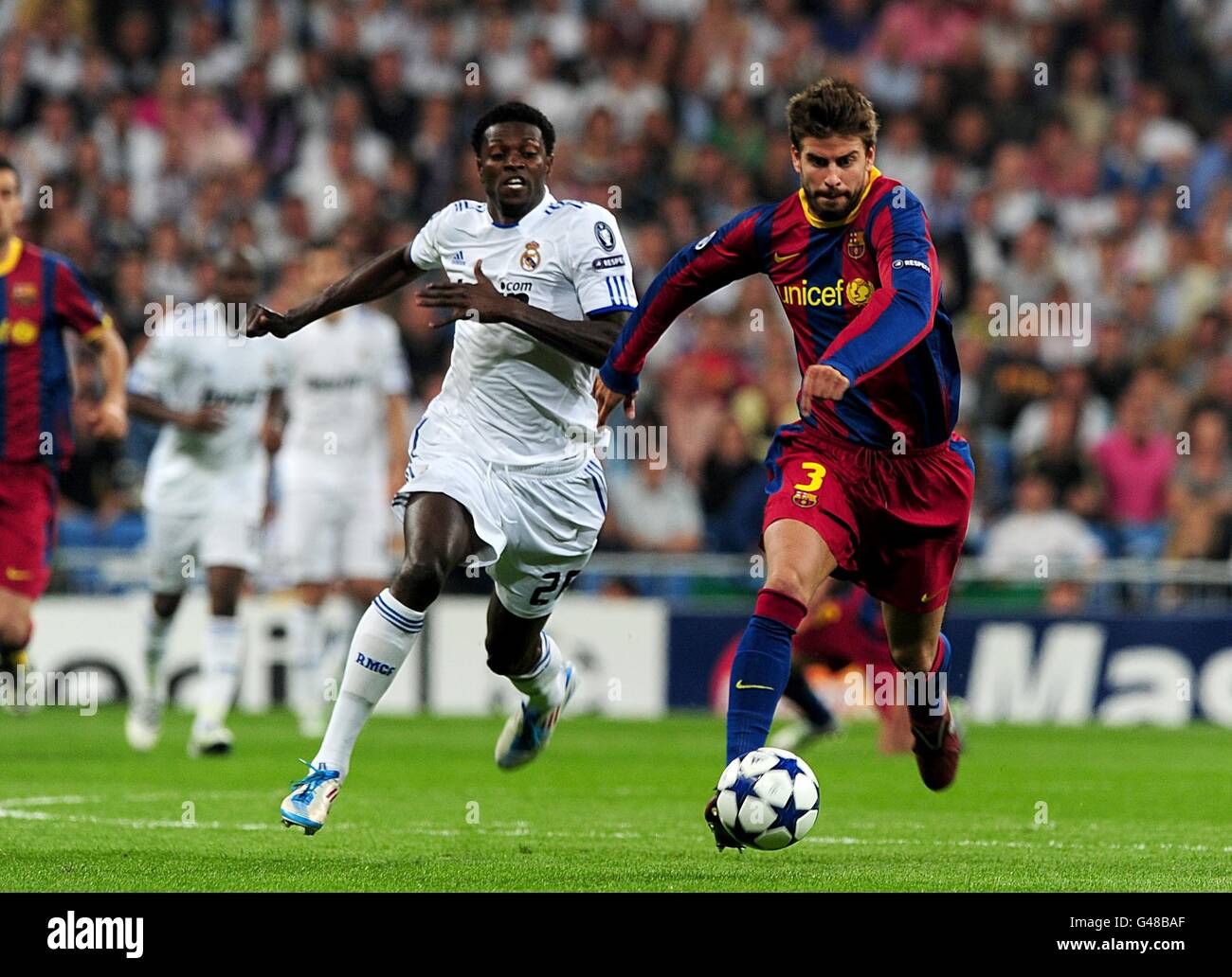 Real Madrid's Emmanuel Adebayor (left) and Barcelona's Gerard Pique (right) in action Stock Photo