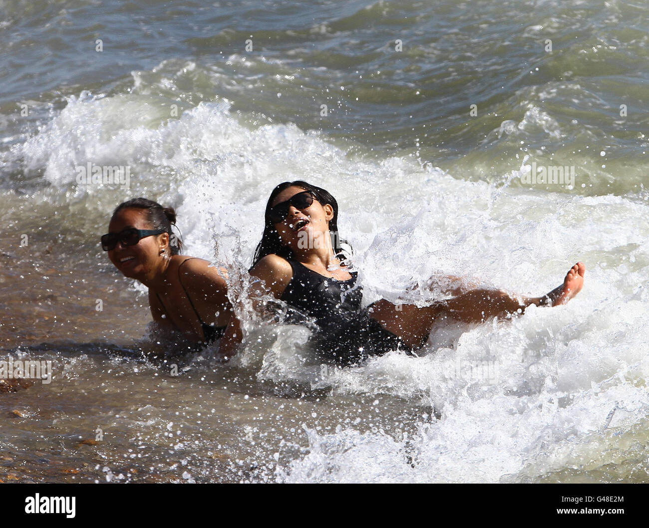Two women enjoy the sunshine in Brighton, East Sussex, as the warm weather continues into the weekend. Stock Photo