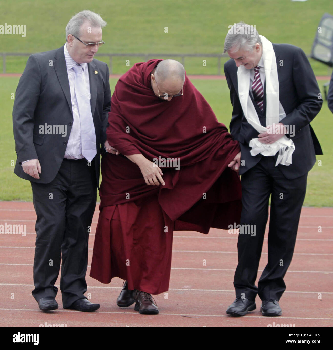 Tibet's spiritual leader, the Dalai Lama (centre), pauses to avoid treading on an earthworm on his way to an address at the University of Limerick on 'the Power of Forgiveness'. Stock Photo