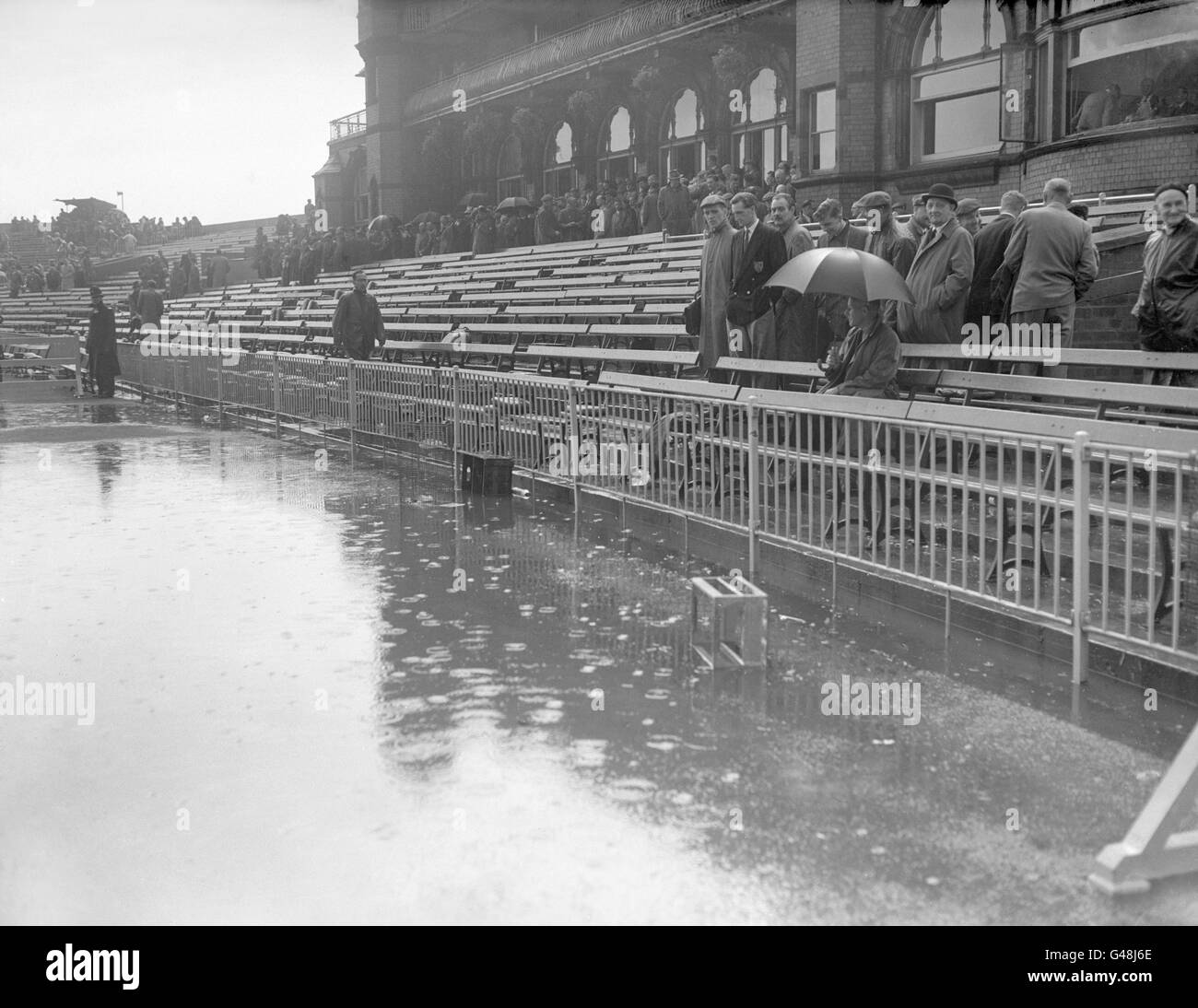 Spectators leave the pavilion at Old Trafford after severe rain flooded the pitch Stock Photo