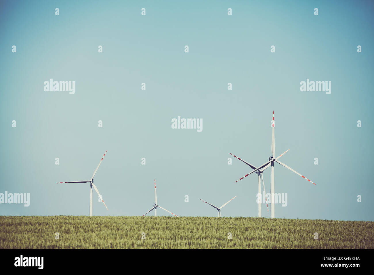 Old film retro toned windmills on a cereal field, alternative energy concept. Stock Photo