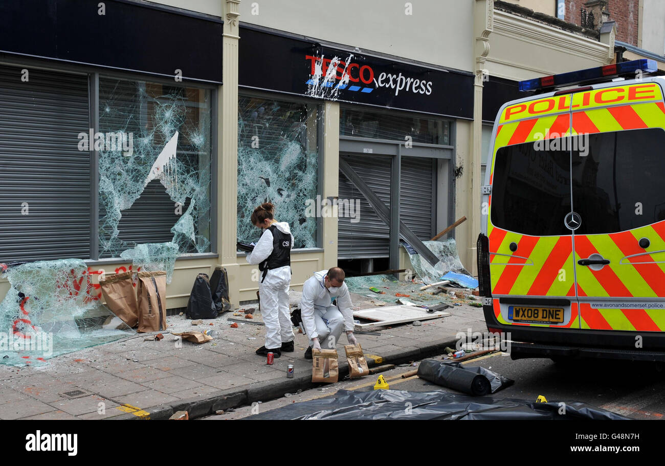 A police Crime Scene Investigator (CSI) examines the scene outside a Tesco Express after eight police officers were injured after a riot broke out when around 160 officers in full riot gear swooped on a house in the Stokes Croft area Bristol at around 9.15pm to arrest four people they said were 'a real threat to the local community'. Stock Photo