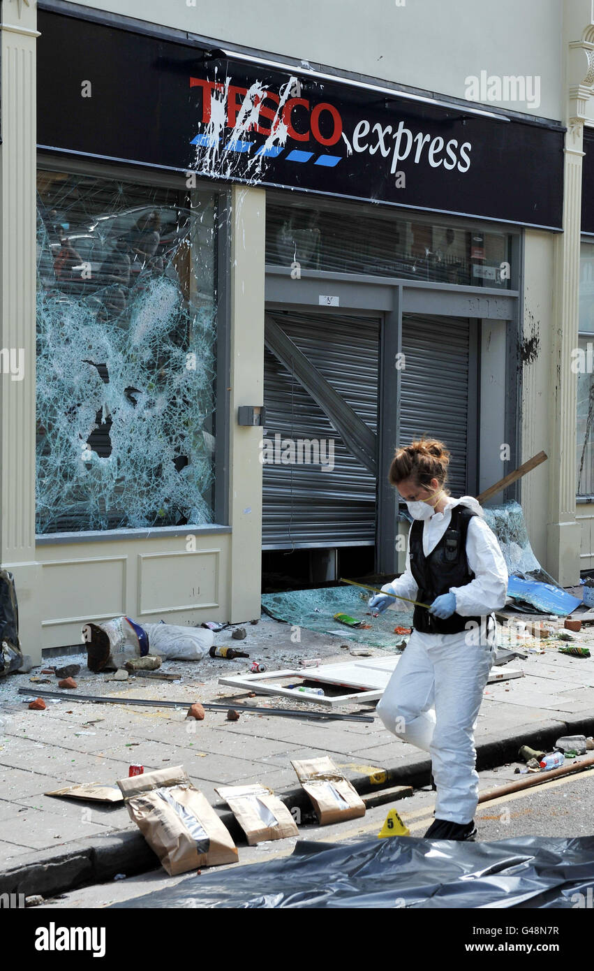 A police Crime Scene Investigator (CSI) examines the scene outside a Tesco Express after eight police officers were injured after a riot broke out when around 160 officers in full riot gear swooped on a house in the Stokes Croft area Bristol at around 9.15pm to arrest four people they said were 'a real threat to the local community'. Stock Photo