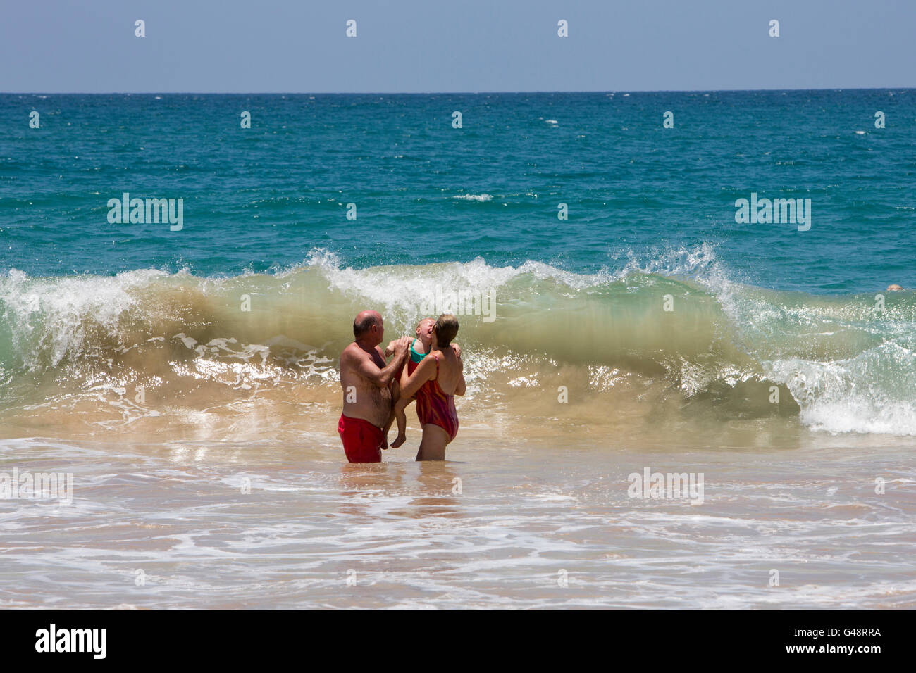 Sri Lanka, Mirissa beach, tourist couple endangering distressed young child in powerful waves Stock Photo