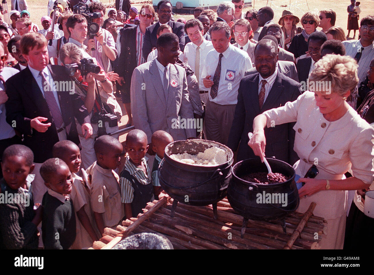 Children wait in line as the Princes of Wales lends a hand to serve the food at the Child Feeding Scheme at Nemazuva Primary School in Zimbabwe. Stock Photo