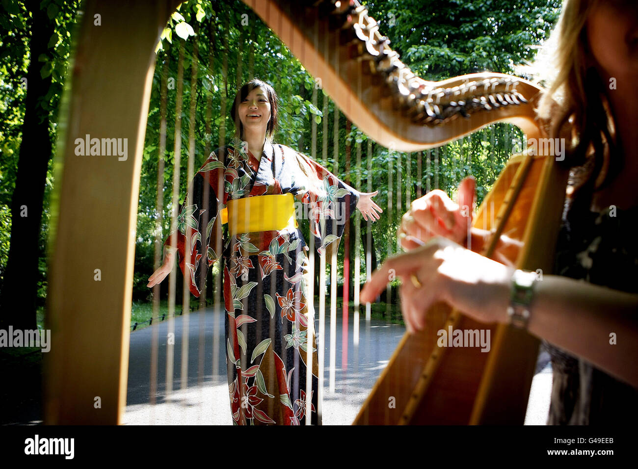 Chika Usami is pictured through Irish Musician Moya Brennan's harp in St. Stephen's Green, Dublin, during a photo call to launch the 'In Solidarity with the People of Japan' music concert featuring top Irish Traditional Musicians to raise money to help the victims of the Japanese Earthquake. Stock Photo