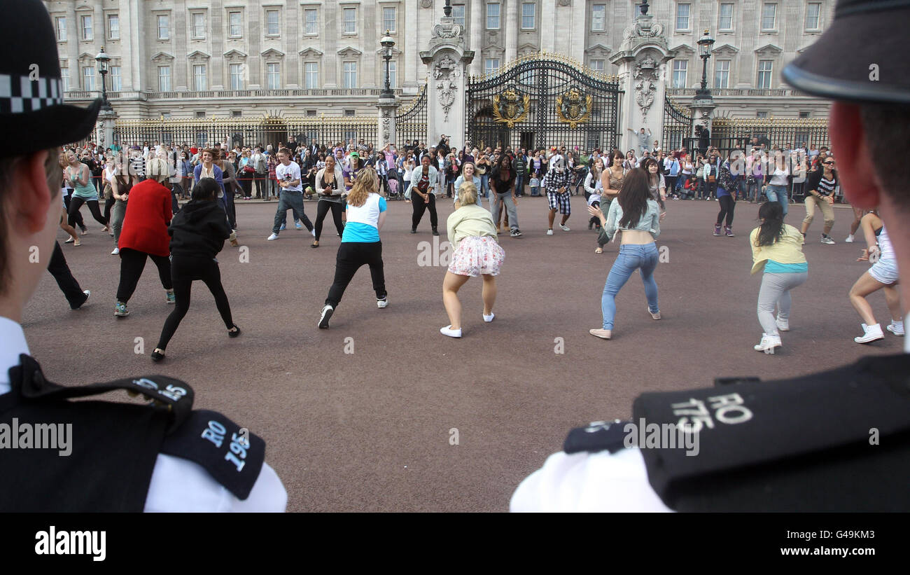 Police officers watch students from the University of East London dance in the Big Dance Royal Flashmob outside Buckingham Palace, London. Stock Photo