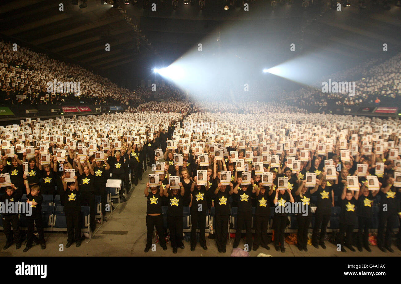 Around 10,000 members of the Rock Choir hold up posters showing pictures of missing children, at Wembley Arena, north London, during a photocall organised by the Miles for Missing people charity, to highlight International Missing Children's Day 2011 on May 25. Stock Photo