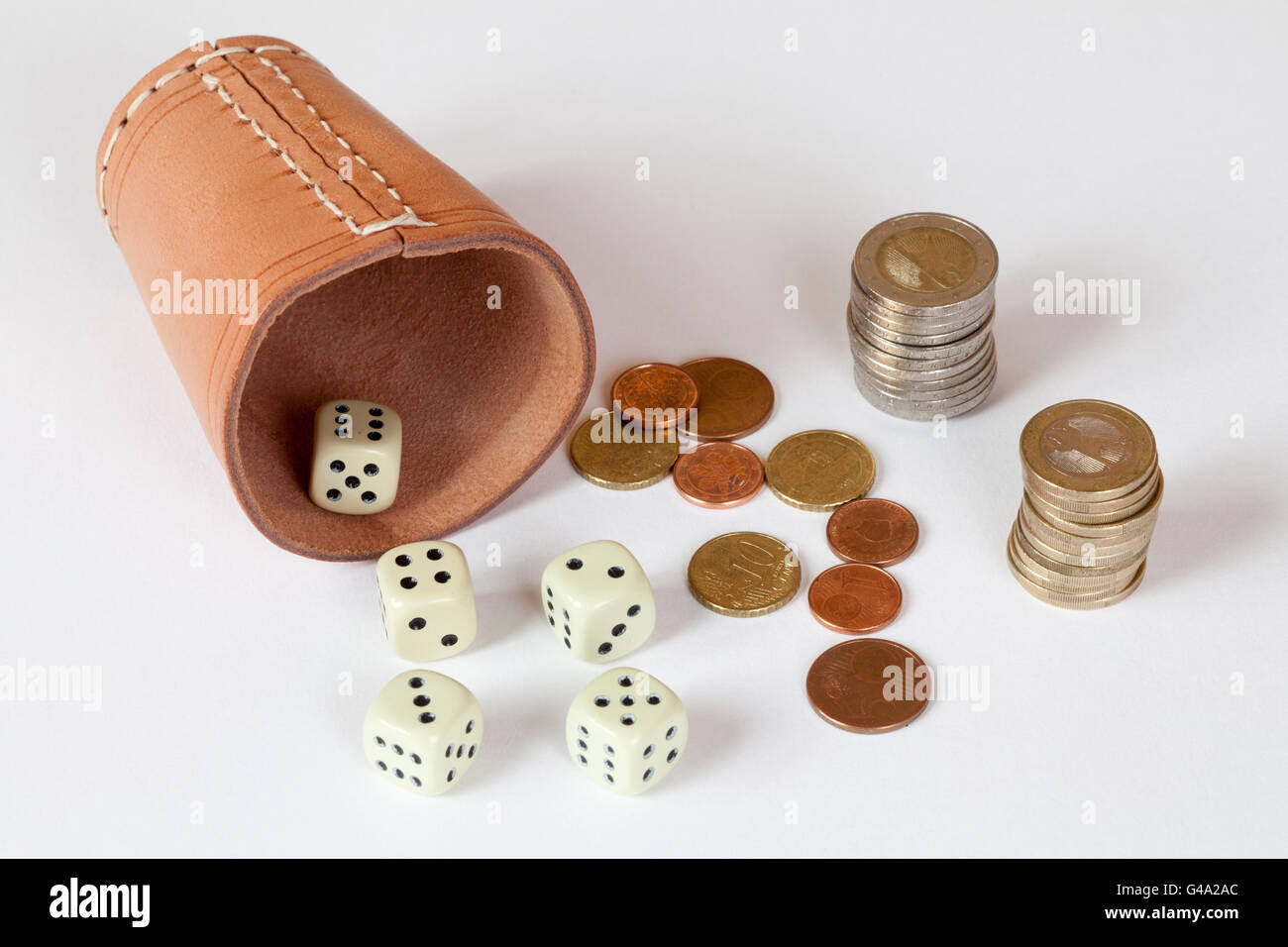 Dice cup with dice and stacked euro coins, symbolic image for gambling