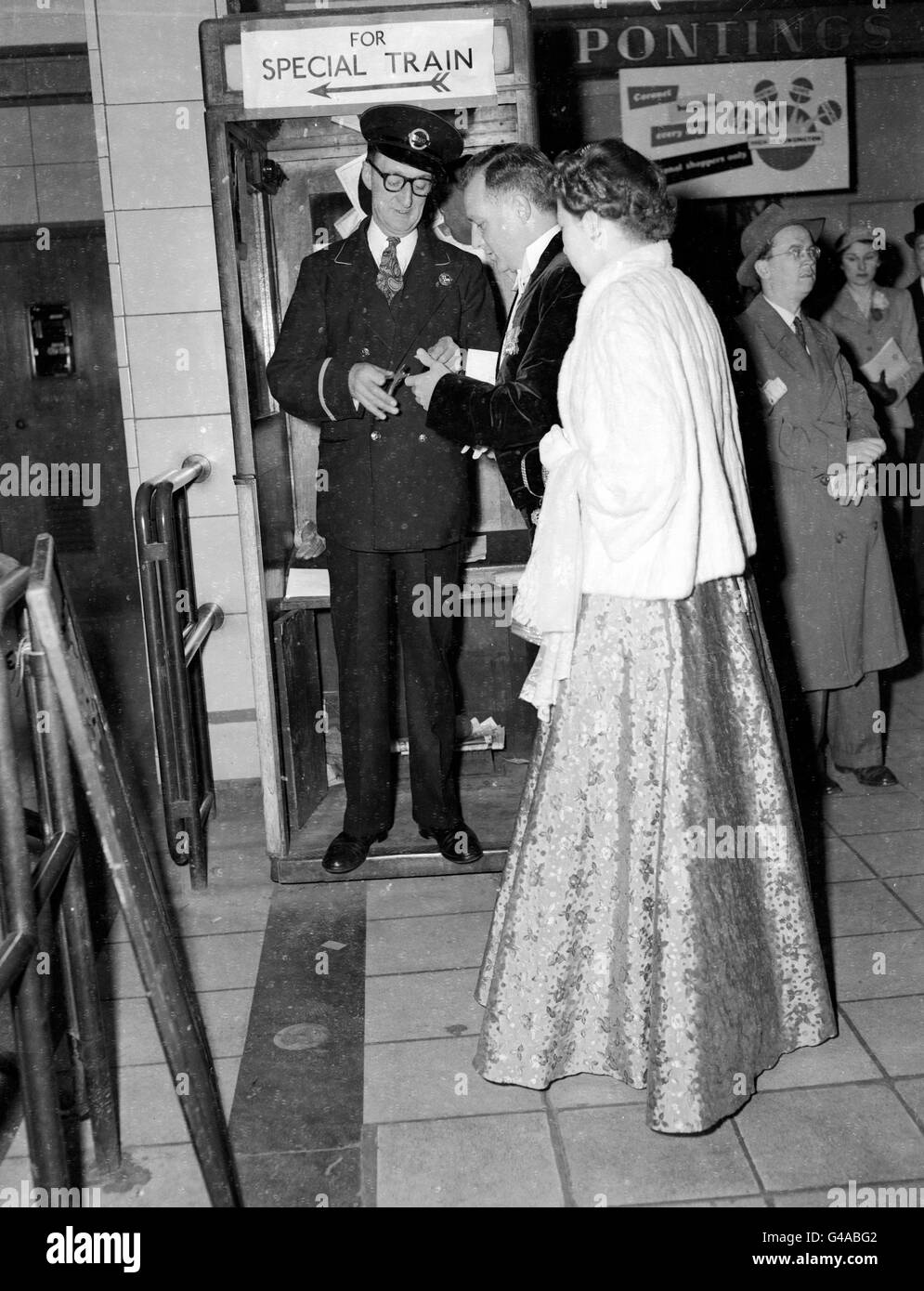 Robert Allan DSO, OBE, MP for Paddington South, and his wife, have their tickets clipped at High Street Kensington Underground station. They traveled by the special 'Silver Train', the only train to stop at Westminster for the Queen's Coronation. *Damaged Negative* Stock Photo