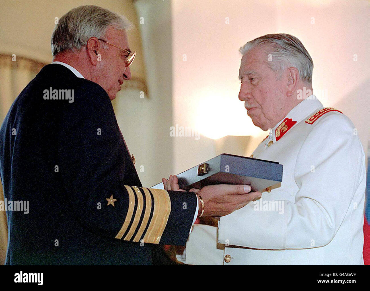 General Augusto Pinochet (R), commander of the Chilean Armed Forces, receives a ceremonial sword 28 January from Air Force General Fernando Rojas during a ceremony in Santiago honoring the Chilean strongman. He is scheduled to retire from his post in March and take up a lifetime seat in the Chilean senate. PA NEWS PHOTO Stock Photo