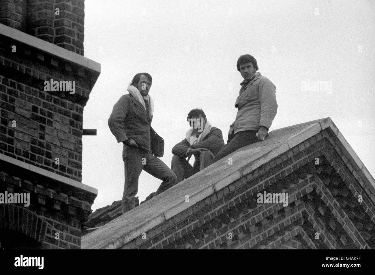 Three prisoners, Robert Walsh, Stephen Blake and Martin Coughlan, stand on the roof of 'D' Block at Wormwood Scrubs Prison, London during a protest by the three inmates. They pelted prison officers with slates from the roof and waved the Irish tricolour flag, demanding 'more humane prison visits.' Stock Photo