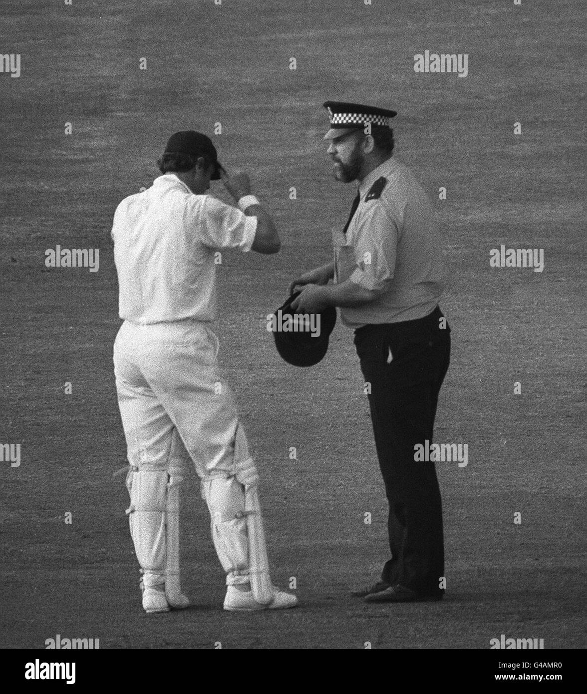 PA NEWS PHOTO 11/8/77 ENGLAND OPENER GEOFF BOYCOTT KNOCKED UP HIS 100TH CENTURY AT HEADINGLEY DURING THE FOURTH TEST AGAINST AUSTRALIA. HE GETS A REPLACEMENT CAP FROM A POLICEMAN AFTER LOSING HIS IN THE CROWD THAT ENGULFED HIM. A FAN BROUGHT BACK HIS ORIGINAL CAP BEFORE THE RESUMPTION OF PLAY AND BOYCOTT WENT ON TO 110 NOT OUT. Stock Photo
