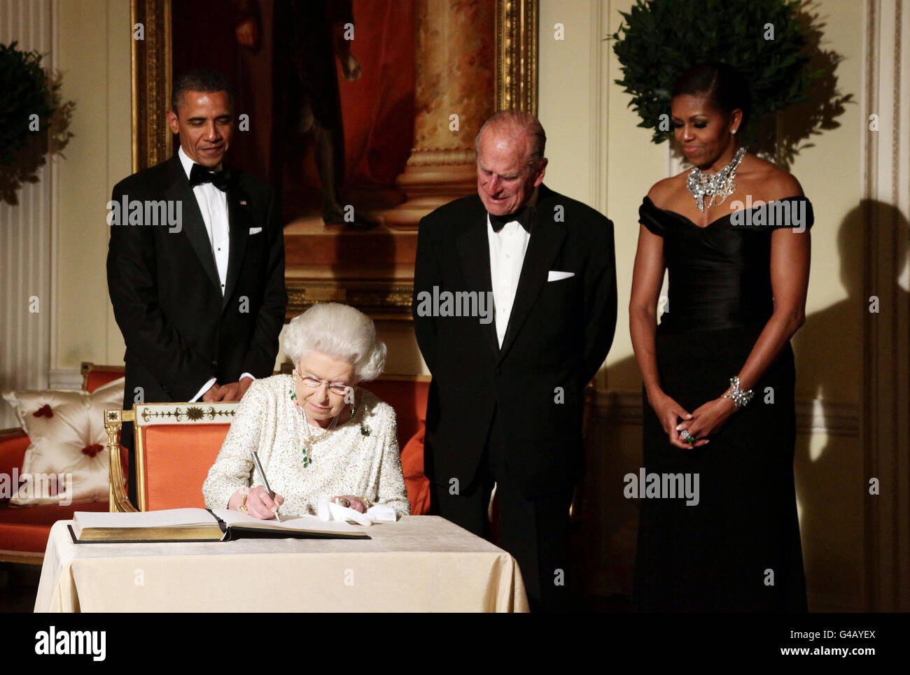 Queen Elizabeth II signs the guest book as she bids farewell to US President Barack Obama and First Lady Michelle Obama, watch by the Duke of Edinburgh at Winfield House - the residence of the Ambassador of the United States of America - in Regent's Park, London. Stock Photo