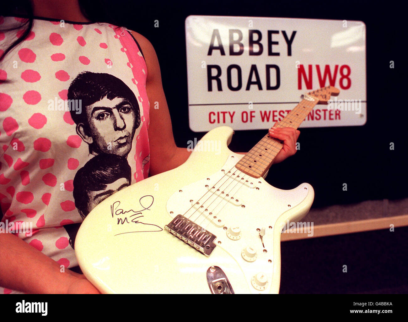 An original 1960's sleeveless 'Beatles' dress printed with facial portraits of the four members of the band, a Fender Squier Stratocaster electric guitar signed by Paul McCartney and an unused enamel street sign for the road their recording studio made famous - Abbey Road in north London - on show at Christie's Auction House in London today (Tuesday) ahead of their sale on April 30th. Photo by Ben Curtis/PA Stock Photo