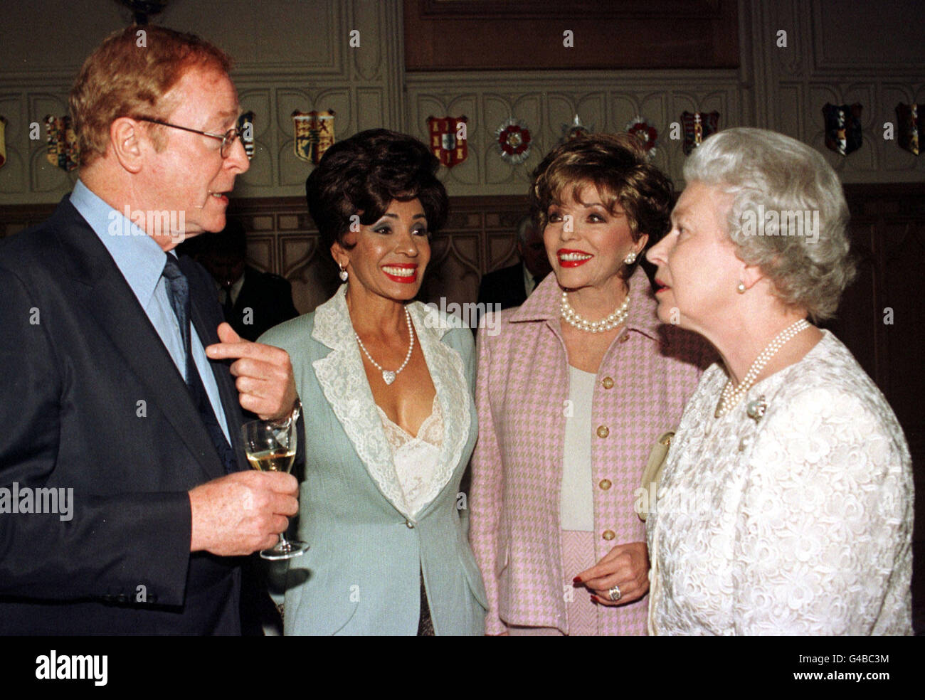 Left to right: Actor, Michael Caine; singer Shirley Bassey and actress, Joan Collins chat to the Queen during a reception for the British Arts at Windsor Castle tonight (Wednesday). WPA ROTA Photograph by Fiona Hanson/PA Stock Photo