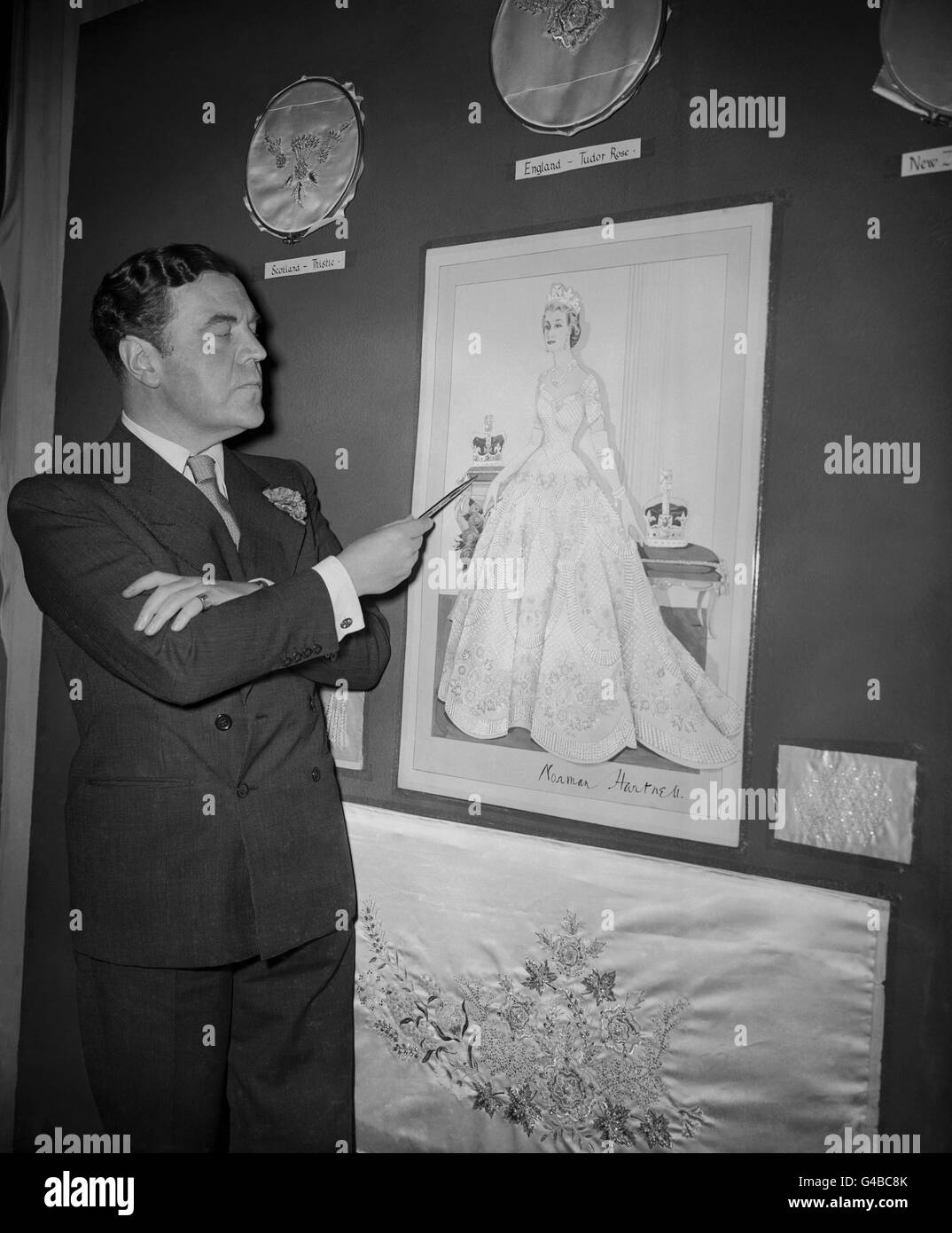 Norman Hartnell, the Royal fashion designer, pointing out the finer points of the Coronation dress he has designed for Queen Elizabeth II. Stock Photo