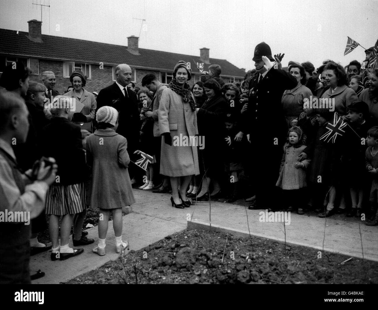 PA NEWS PHOTO 20/4/59 WOMEN AND CHILDREN PRESS CLOSE TO THE QUEEN AS SHE LEAVES AFTER A VISIT TO A NEW HOME DURING HER THREE-HOUR TOUR OF STEVENAGE NEW TOWN, HERTFORDSHIRE. THE QUEEN IS WEARING A COAT OF PALE MUSTARD COLOURED WOOL WITH A OCELOT FUR COLLAR AND A SMALL VELVET HAT OF MATCHING PALE MUSTARD VELVET Stock Photo