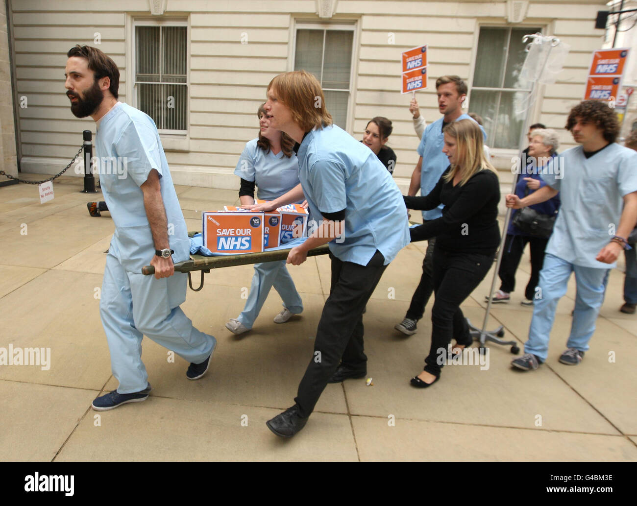 Members of the 38 Degrees protest group use a stretcher to deliver a 400,000 signature 'Save the NHS' petition to the Department of Health, in Westminster, central London. Stock Photo