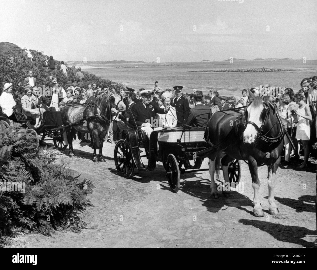 Queen Elizabeth II is seen at Tresco, Isles of Scilly, in a pony-trap with the Prince of Wales (back to pony in the first conveyance), with Commander Thomas Dorrien-Smith driving. In the second trap is Prince Philip, the Duke of Edinburgh, and Anne, Princess Royal, on the rear seat. Stock Photo