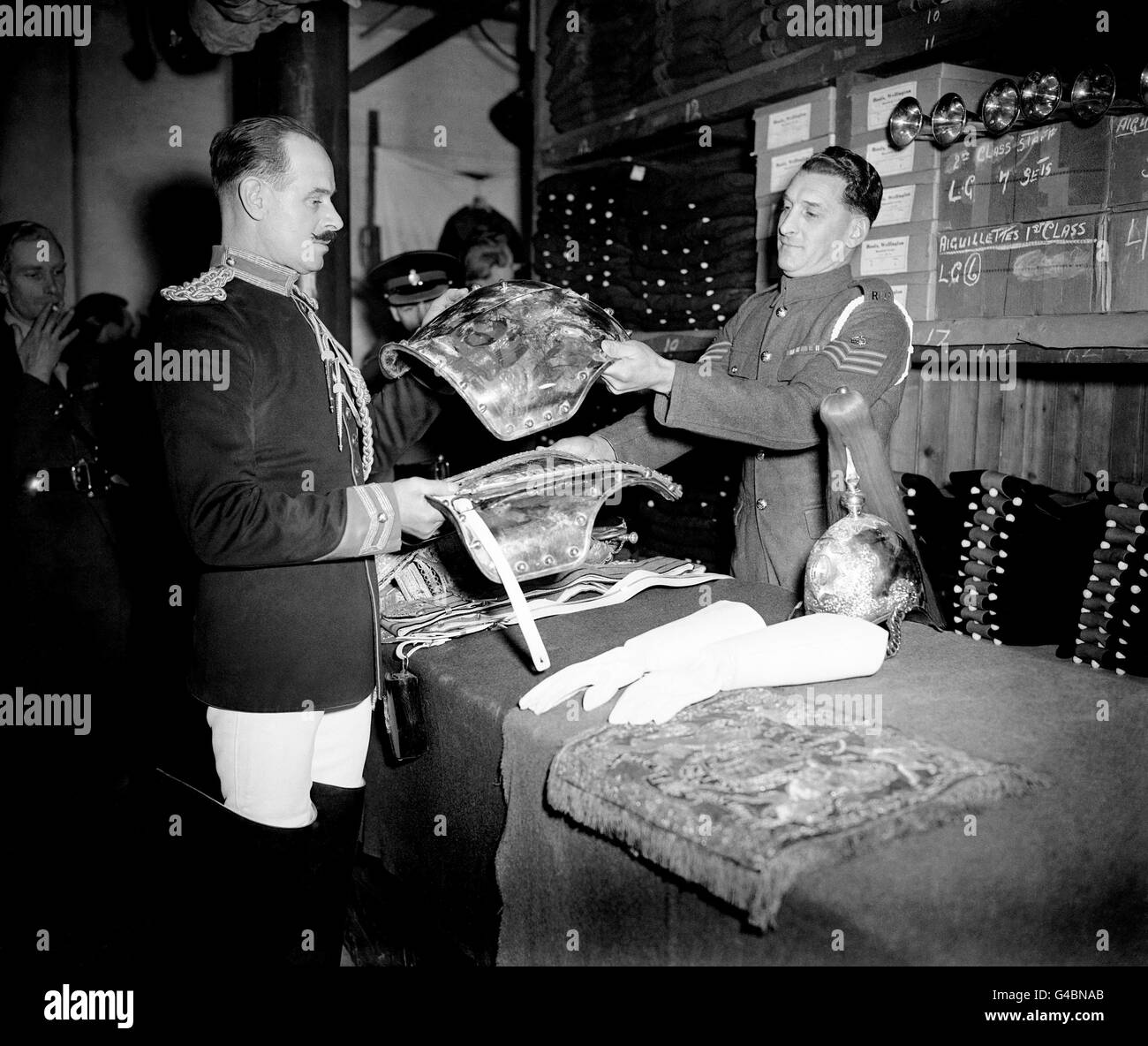 Men of the Royal Horse Guards who will form part of the Sovereign's Escort at the Coronation checking the ceremonial full dress equipment which they will be wearing. Corporal of Horse J. Hammond, left, receives his uniform from Corporal of Horse J. Peart at Knightsbridge Barracks, London. Stock Photo